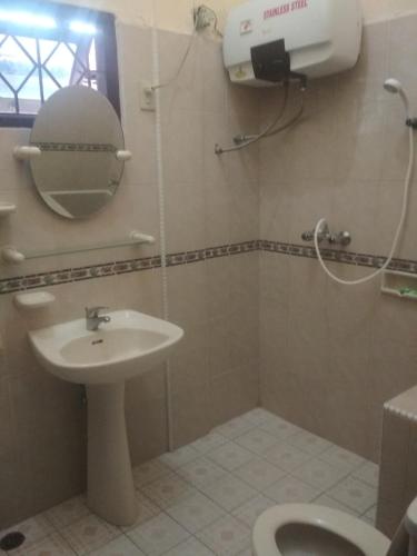a bathroom with a sink and a toilet and a mirror at Sapo Karo Rest House in Berastagi