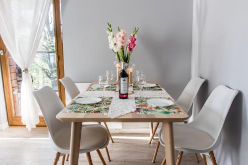stół z białymi krzesłami i wazon kwiatów w obiekcie Luxury Apartment Bursztynowa w Gdańsku