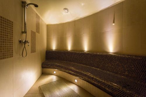 eine Dusche mit einer Bank im Bad mit Beleuchtung in der Unterkunft Qubus Hotel Kielce in Kielce