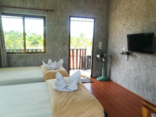 a bedroom with three beds with white towels on them at BN Resort in Ban Nong Chum Saeng