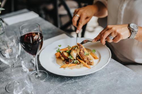 a person eating a plate of food with a glass of wine at Best Western Valhall Park Hotell in Ängelholm