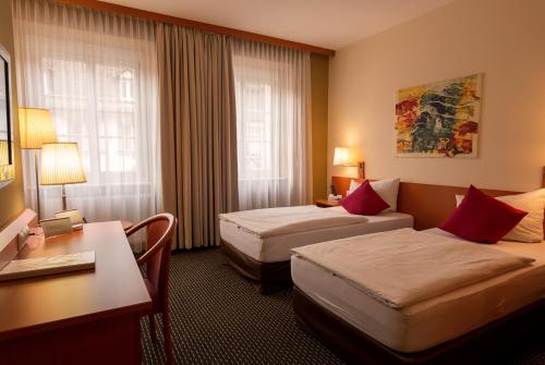a hotel room with two beds and a desk at Central Hotel Löwen in Feldkirch