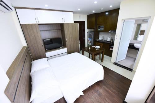 a bedroom with a white bed and a kitchen at Granda Legend Apartment in Hanoi