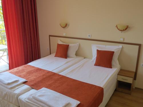 two beds in a hotel room with red curtains at Family Hotel Dayana Beach in Sinemorets