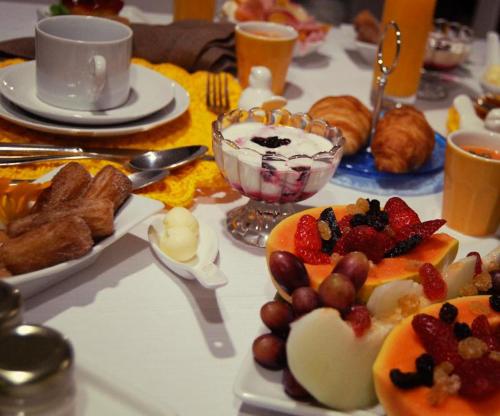a table topped with plates of fruit and pastries at Pousada Polessas in Visconde De Maua