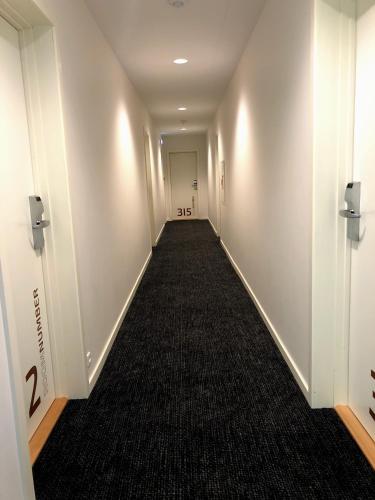 a long hallway with white walls and a black carpet at Hotel Skivehus in Skive