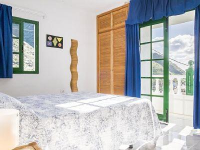 1 dormitorio con 1 cama con cortinas azules y ventana en Casita Canaria, en Santa Cruz de Tenerife