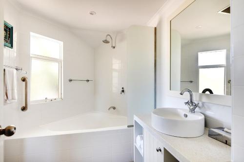 a white bathroom with a sink and a tub at Seashells Broome in Broome