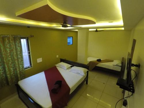 a room with two beds and a tv in it at Hotel Royal Inn in Hiriyūr