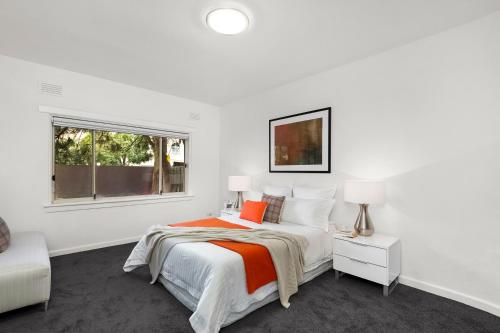 a white bedroom with a bed and a window at Beachfront Apartment in Melbourne