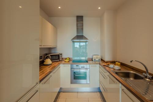 una cocina con armarios blancos y fregadero en PREMIER SUITES Dublin, Sandyford en Sandyford