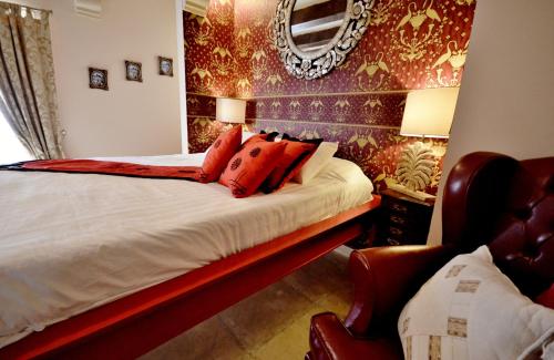 a bedroom with a bed with red pillows and a mirror at Chapel 5 Boutique Suites B&B in Naxxar