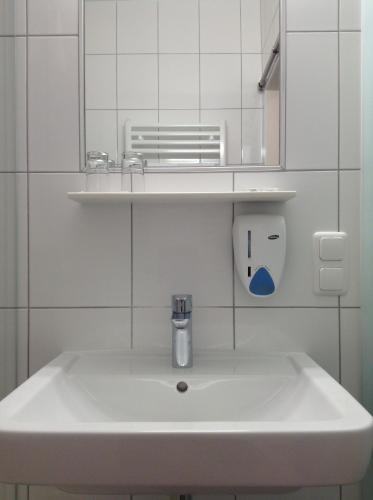 un lavabo blanco en un baño de azulejos blancos en Leonsteinerhof, en Leonstein