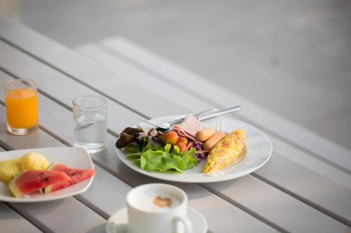 two plates of food on a table with a salad and orange juice at Siambeach Resort in Cha Am