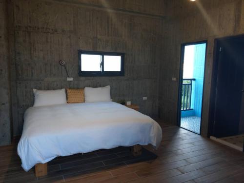 a bedroom with a large white bed and a window at Relaxing Hotel in Donggang