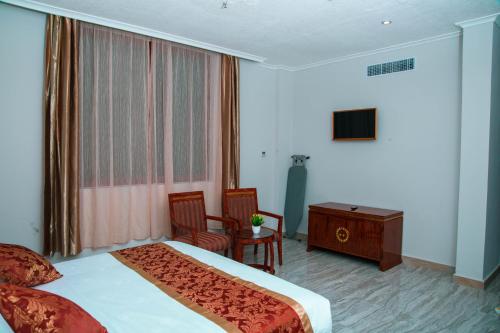 a hotel room with a bed and a desk and a window at Tiffany Diamond Hotels LTD - Makunganya in Dar es Salaam
