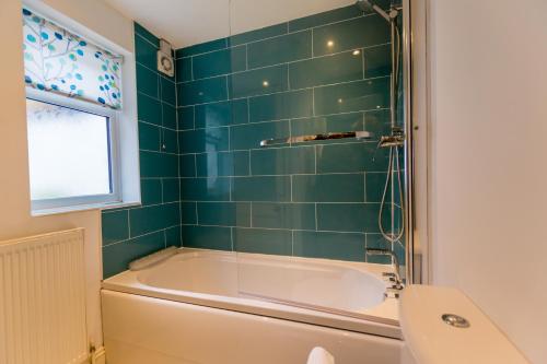 a bathroom with a tub and a green tiled wall at 3 Buckingham Street in York