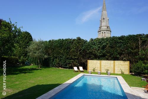 basen w ogrodzie z wieżą zegarową w tle w obiekcie Ker Feuchidoul w mieście Merlevenez