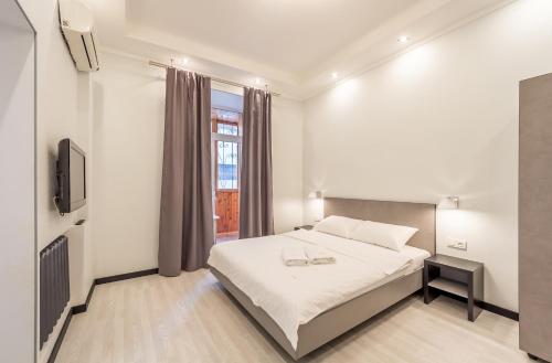 a white bedroom with a bed and a tv at Central Dayflat Apartments in Kyiv