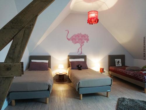 dwa łóżka w pokoju na poddaszu z dinozaurem na ścianie w obiekcie Ker Feuchidoul w mieście Merlevenez