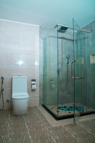 a bathroom with a toilet and a glass shower at Tiffany Diamond Hotels LTD - Makunganya in Dar es Salaam