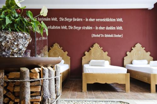 a room with three beds and a wall with writing at Sepp & Hannis Suiten im Dorf in Neustift im Stubaital