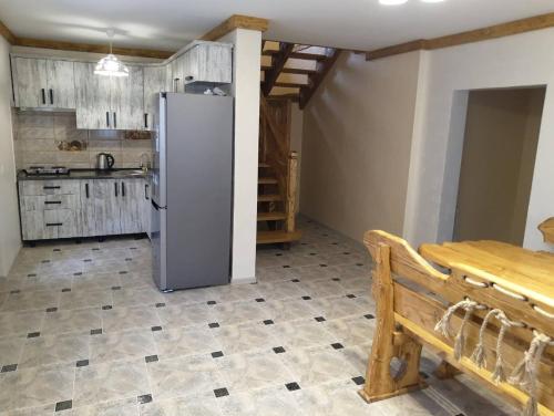 eine Küche mit einem Kühlschrank, einem Tisch und einer Bank in der Unterkunft Котедж Зґарда in Jaremtsche