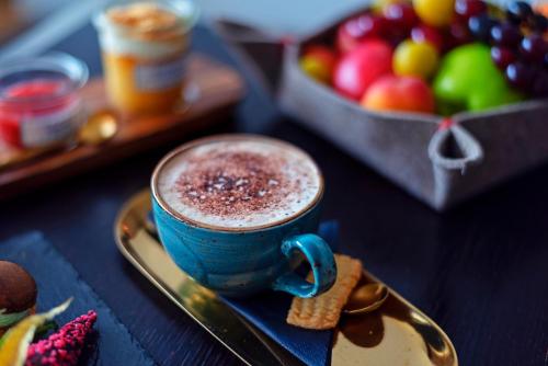 a blue cup of cocoa next to a plate of fruit at Le Mirabeau Resort & Spa in Zermatt