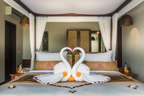 two white swans are sitting on a bed at Ayuterra Resort in Ubud