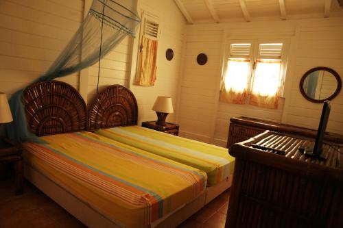 1 dormitorio con cama y espejo en BUNGALOW BASSIN TROUVE, en Sainte-Anne