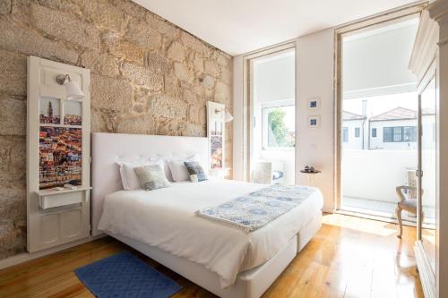 um quarto com uma cama grande e uma parede de pedra em Trindade Premium Suites & Apartments no Porto