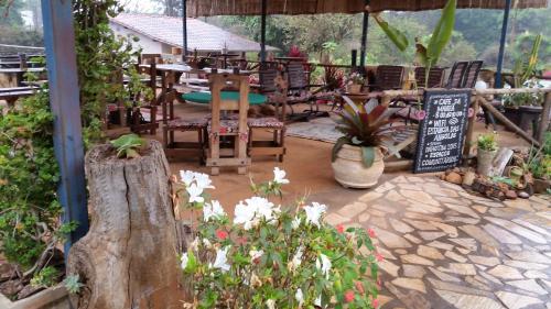 a patio with a restaurant with tables and chairs and flowers at Estância das Angolas - Inhotim in Brumadinho