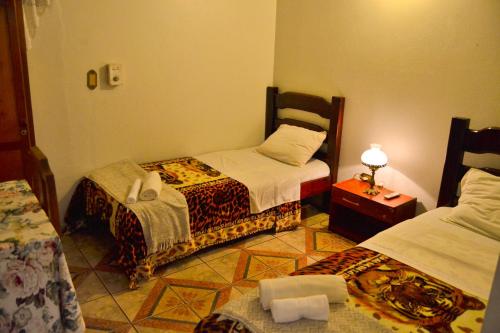 a bedroom with two beds and a table with a lamp at Hotel & Restaurante Guarania in Ciudad del Este