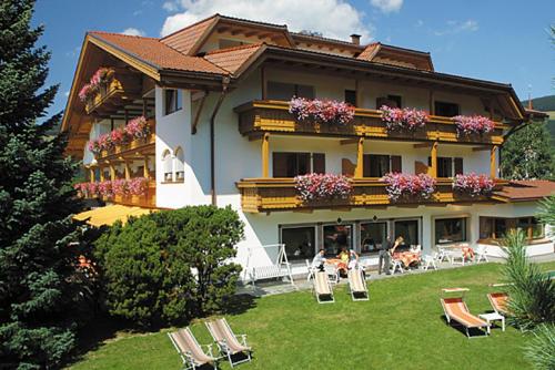 a large building with chairs and people sitting in the yard at Hotel Markushof 3***S in Valdaora