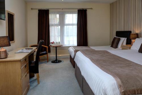 a hotel room with two beds and a desk at Northallerton Motel in Northallerton
