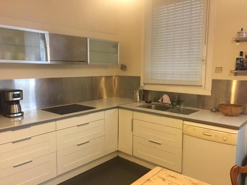 a kitchen with white cabinets and a sink at Les Chambres des Barques in Narbonne