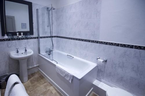 a bathroom with a sink and a tub and a toilet at The White Hart Inn in Winchcombe