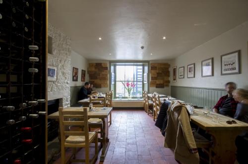 ein Restaurant mit Holztischen und -stühlen und einem Fenster in der Unterkunft The White Hart Inn in Winchcombe