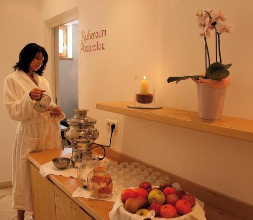 a woman standing in a room with a table with fruit at Hotel Markushof 3***S in Valdaora