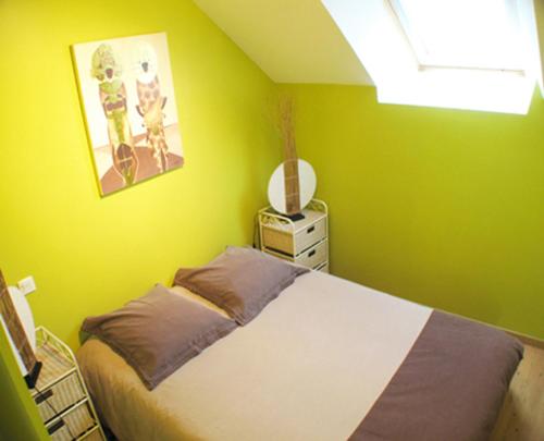 a bedroom with a bed with a green wall at L'Eternet in Malansac