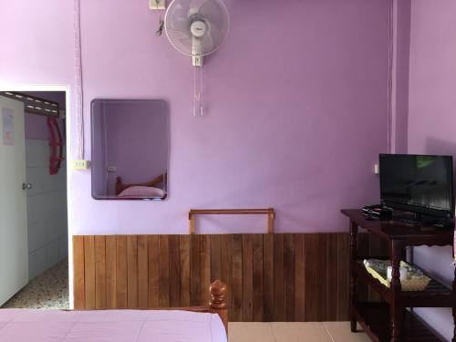 a bedroom with a purple wall with a fan at Panamma Hill Resort in Khao Kho