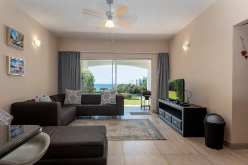 a living room with a couch and a television at Santorini Kallisti 7 (Family Only) in Ballito