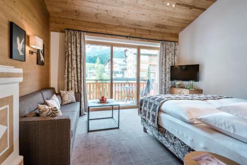 a bedroom with a bed and a large window at Hotel Auenhof in Lech am Arlberg