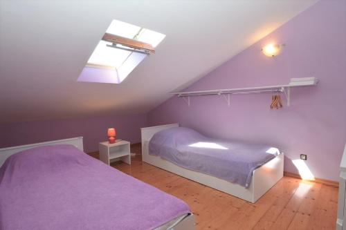 a purple bedroom with two beds and a skylight at House Luciana in Mali Lošinj