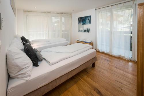 two beds in a room with a window at Casa Della Vita by Zermatt Premium Apartments in Zermatt