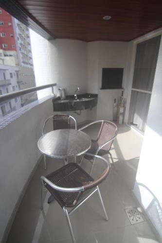 balcón con 3 sillas, mesa y lavamanos en Lindo Apartamento Vista Mar, en Balneário Camboriú