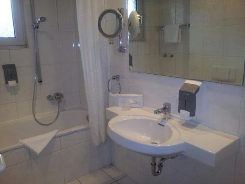 a white bathroom with a sink and a shower at T&T by Thiesmann in Mülheim an der Ruhr