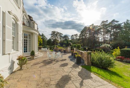 a patio with white chairs in a garden at Gorse Hill Hotel in Woking