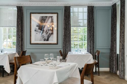 a dining room with white tables and windows at Gorse Hill Hotel in Woking