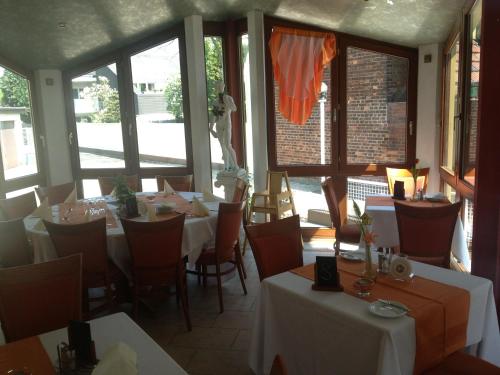 a restaurant with white tables and chairs and windows at Hotel Flora in Dormagen